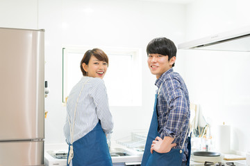 Fototapeta premium キッチンで振り返るカップル（エプロン着用）