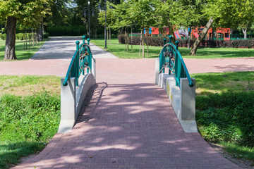 Romantic scenery of a Tourkise foot bridge in a green park