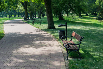 Wooden bench in a green park next to a foot path