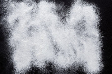 Baking concept on black background, sprinkled flour with copy space