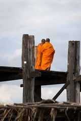 Buddhist monks in conversation as they cross the U Bein bridge, Taungthaman Lake, Mandalay, Myanmar