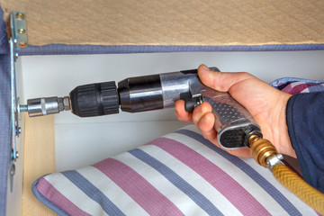Close-up hands of a carpenter with pneumatic wrench.