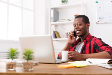Obraz premium Young black businessman talking on mobile in modern white office