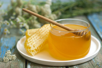 Honey in a glass jar and honey in honeycombs on an old wooden background