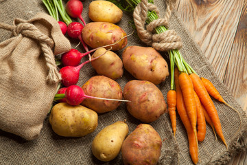 Potatoes, carrot and radishes. Raw new potato. Fresh natural vegetables. Organic food on wooden...
