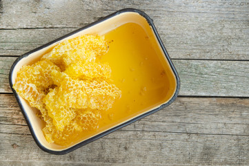Yellow honeycombs in metallic enameled form on the old wooden background