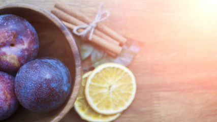 Plum in a wooden dish, cinnamon, orange
