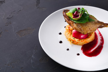 Restaurant meals. Duck confit with vegetables on black background