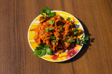 Chicken gizzard stew in plate on wooden table
