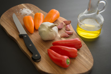 Small red and yellow peppers with garlic on chopping board