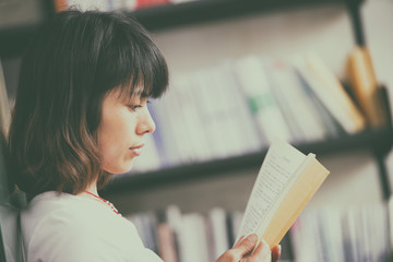 Pretty young woman enjoying reading a book in bookstore