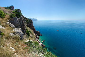 Rocky shore coast of tropical azure sea. The Black Sea, Crimea. Hot, sunny summer day