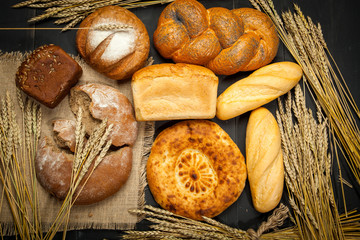 Assortment different types of bread. Rustic style bread on brown wooden table. Top view or flat lay. Copy space.