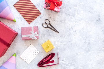 Preparing to celebration. Colored gift boxes and party hats on grey stone background top view copyspace