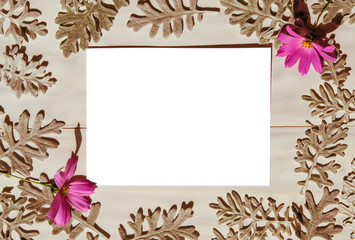 Abstract background, blank white sheet of paper on a light wooden table with a pattern of brown leaves and pink flowers, mock up