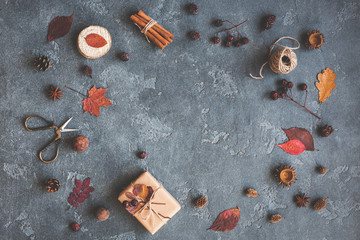 Autumn composition. Gift, autumn leaves, cinnamon sticks, anise stars, pine cones on black background. Flat lay, top view, copy space