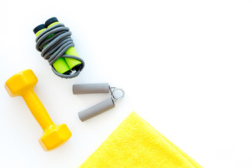 Equipment for fitness. Jump rope, dumbbells and expander on white background top view copyspace