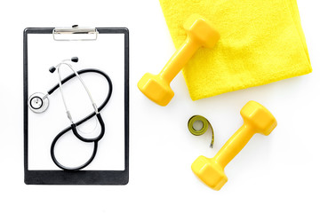 Sport and health. Fitness. Dumbbells and stethoscope on white background top view