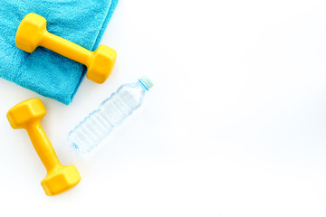 Fitness background. Dumbbells, towel and water on white background top view copyspace