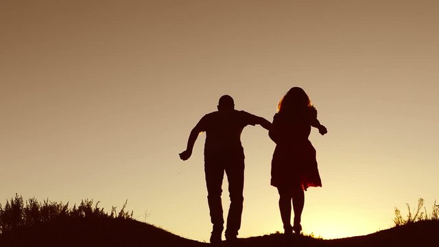 Man and woman couple in love silhouette jumping in slow motion video. Man and woman joy running sunlight and jumping on nature silhouette