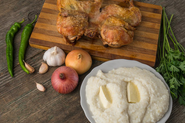 Fried chicken, ghomi and vegetables on an old wooden board, Georgia, Samegrelo