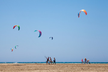 People practicing Kitesurfing. Beach on the peninsula Prasonisi, Rhodes. Colorful kites on the sea shore. Blue sea and windsurfing.