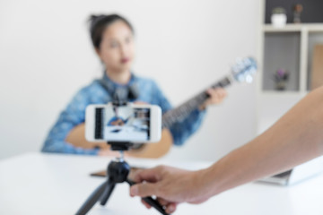 social media learning concept, relaxing and playing guitar, Young woman concentrating learn and play the guitar to a tutorial on lesson online, while she recording music video in camera at home