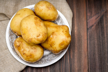 Raw potatoes on a brown wooden background