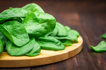 Fresh juicy spinach leaves on a wooden brown table. Natural products, greens, healthy food, vitamins.