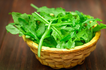 Fresh juicy leaves of arugula on a brown wooden table.