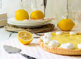 lemon curd tart on a plate with lemon and white background