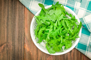 Fresh juicy leaves of arugula on a brown wooden table.