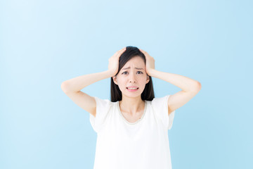 頭を抱える女性・ブルーバック