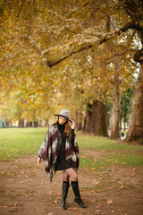 Obraz premium Woman in coat with hat and scarf in autumn park 