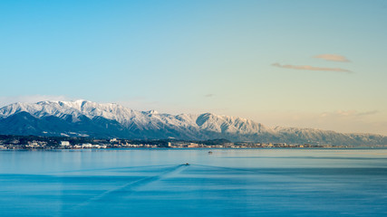 The largest freshwater Biwa Lake, Shiga, Kyoto, Japan in winter. Fantastic freshwater lake scene, snow covered mountain and bright clear blue sky background.