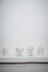 White abstract plaster background with angels and candles, brick underneath. copy space