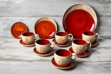 Set of ceramic plates and cups on wooden background 