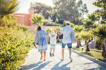 Fototapeta na wymiar Back view of young family walking on park
