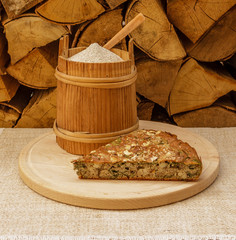 Buckwheat flour in wooden canister and piece of pie on wooden plate