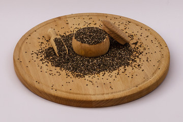 Chia seeds on wooden bowl and in wooden spoon on wooden plate