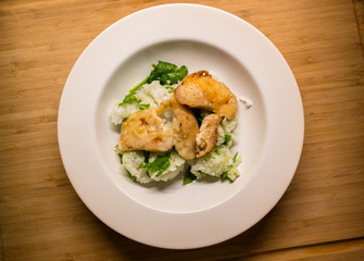 Baked chicken dish with parmesan, spinach and rice on a wooden chopping board