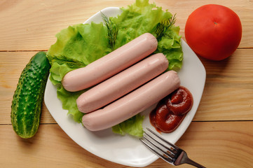 Breakfast is. Sausages on leaves of green salad with tomatoes and cucumber.