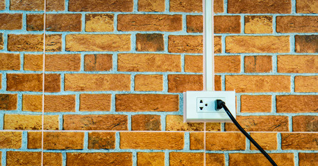  A home electrical outlet on brown brick wall. Outlet, plug, socket on brown brick background....