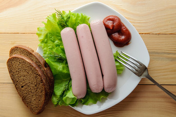 Breakfast man. Sausages on green lettuce leaves with tomato and cucumber.