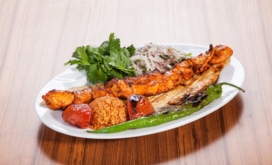 Turkish chicken kebab served with yogurt and vegetables on wooden table