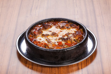 Meat stew served with melted cheese on wooden table