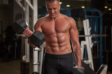 Naklejka premium Young adult bodybuilder lifting weight in gym.