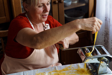 Senior woman making noodles in old fashioned kitchen.