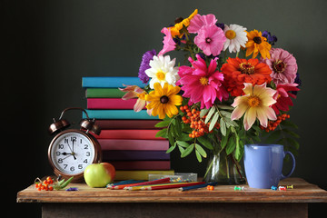 Still life with autumn bouquet, alarm clock and books.