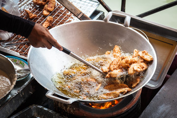 Pattaya city floating open air market in the southeast asian country of Thailand. Person cooking local cuisine in a wok with oil. / Person cooking asian food.